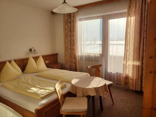 蒂罗尔州基希多夫Appartements Binderhof的一间卧室配有一张床、一张桌子和一个窗户。