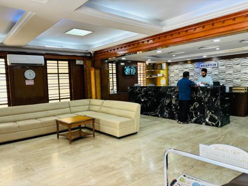 班加罗尔Hotel Chetan International的大厅里长着沙发,两个男人站在柜台上