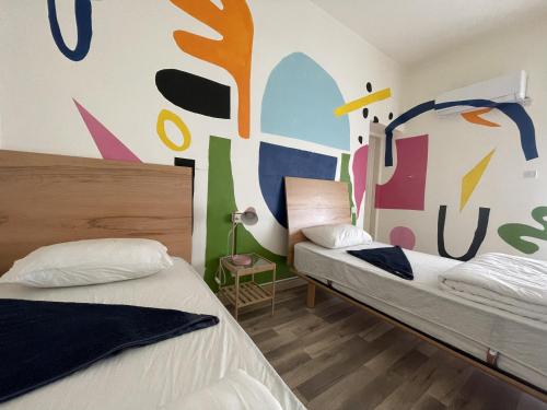 安曼Battuta Hostel的墙上壁画的房间里设有两张床