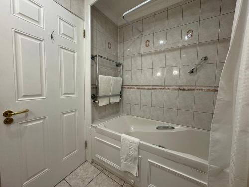 基拉尼The Killarney Grand的白色的浴室设有浴缸和淋浴。
