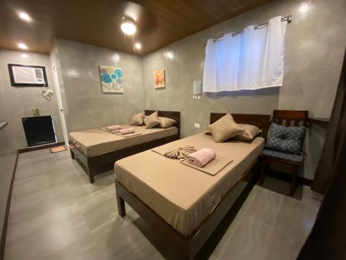 公主港Wilnags Inn Puerto Princesa near airport的一间带两张床和椅子的房间