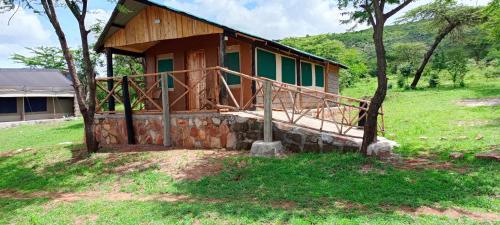 Sekenaniorkaria safari mara camp的一座小房子,位于草木茂密的山丘上,有一棵树