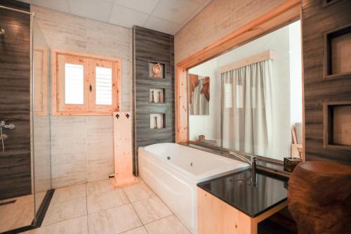 达哈布NEOM DAHAB - - - - - - - - - - - Your new hotel in Dahab with private beach的一间带浴缸和大镜子的浴室