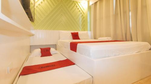 达沃市RedDoorz @ Innzz Apartel的白色客房内的两张床,配有红色和白色床单