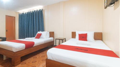 达沃市RedDoorz at Casa Buena Dormitel Davao City的一间设有两张红色和白色床单的房间