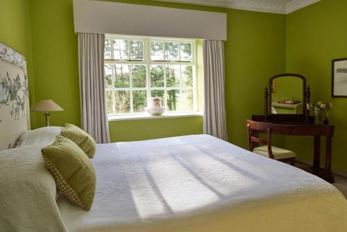 巴利瓦根Gregans Castle Hotel的绿色卧室设有床和窗户