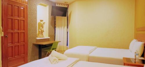 科米坦德多明格斯Hotel Central Comitán的酒店客房设有两张床和电视。