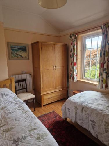 AppinLaich Cottage的一间卧室设有两张床、一个橱柜和一个窗口。