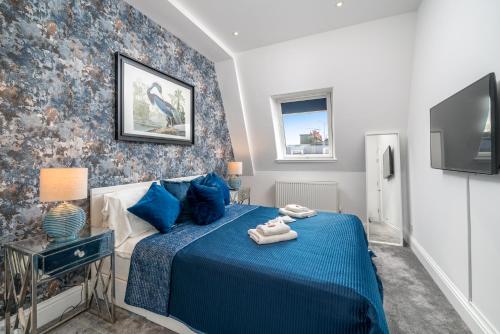 伦敦Niru Experience Royal Deluxe 4BD 2BA Apt的一间卧室配有蓝色的床和电视