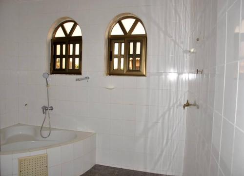 洛美Tatiana City Appartement的带浴缸和水槽的浴室以及2扇窗户。