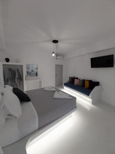 佩里萨East Wind Perissa的一间白色卧室,配有两张床和电视