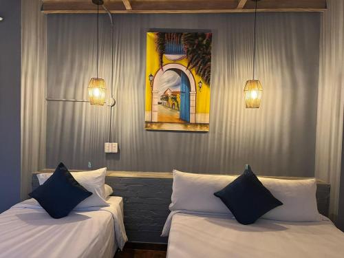 卡塔赫纳马洛卡精品酒店的配有两张床铺的客房配有两盏灯和一幅画