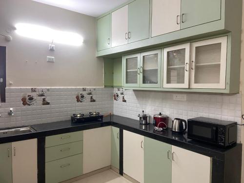 海得拉巴Bigson Service Apartments, Kondapur的厨房配有绿色和白色的橱柜和微波炉