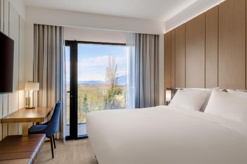 圣朱利安恩因AC Hotel by Marriott Saint-Julien-en-Genevois的配有一张床、一张书桌和一扇窗户的酒店客房