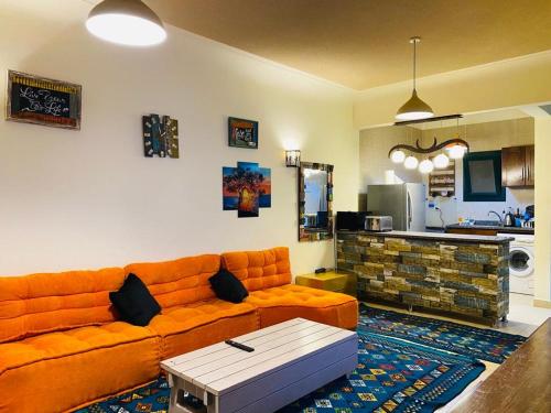 拉斯苏德尔Furnished Chalet Apartment at La Hacienda Ras Sedr的一间带橙色沙发的客厅和一间厨房