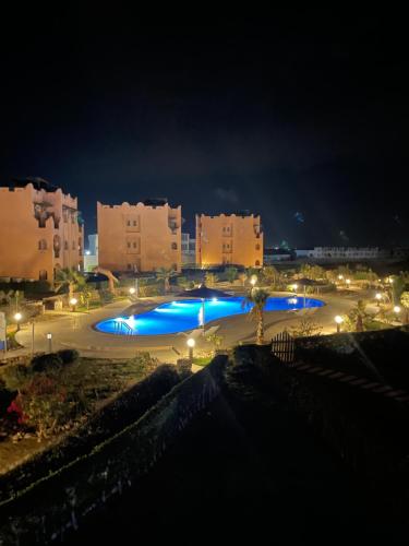 拉斯苏德尔Furnished Chalet Apartment at La Hacienda Ras Sedr的城市的一座大型游泳池,晚上有蓝色的灯光