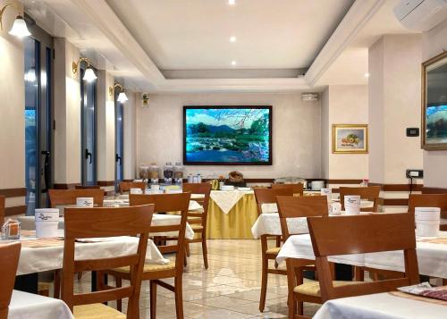 圣佩莱格里诺温泉阿伏伽德罗酒店的一间带桌椅和大屏幕的餐厅