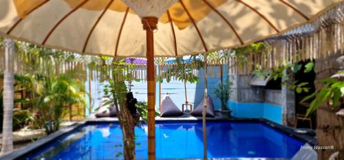 吉利特拉旺安Villas Light House - Eco-Traditional Joglo的游泳池旁配有遮阳伞