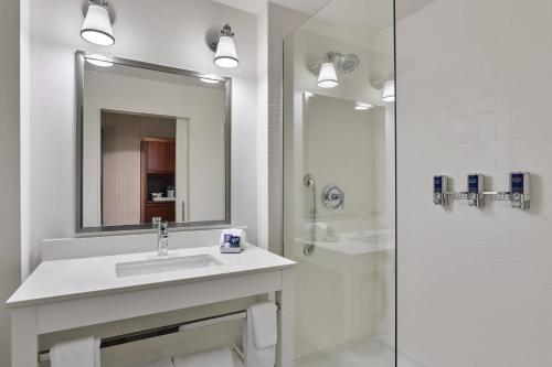 Coppell达拉斯沃思堡机场北福朋喜来登酒店 的白色的浴室设有水槽和淋浴。