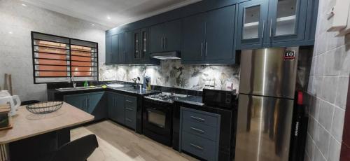 黑角Résidence Axel的厨房配有蓝色橱柜和不锈钢冰箱