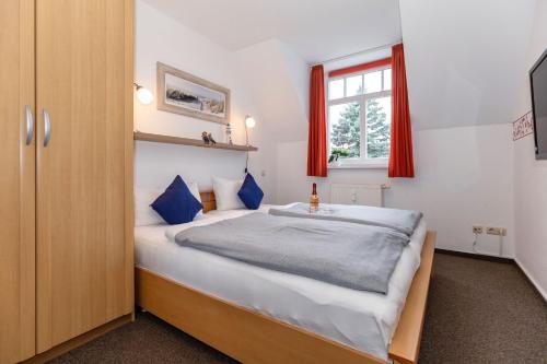 奥斯赛拜-屈隆斯博恩Brücken-Butze Whg 12 Villa Strandburg的一间卧室配有一张带蓝色枕头的床和一扇窗户。