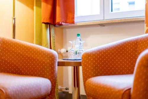 维尔茨堡奥尔特克拉能酒店的2把椅子和1张桌子以及2瓶水