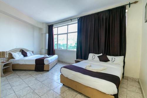 内罗毕Fahari Bliss Hotel的酒店客房设有两张床和窗户。