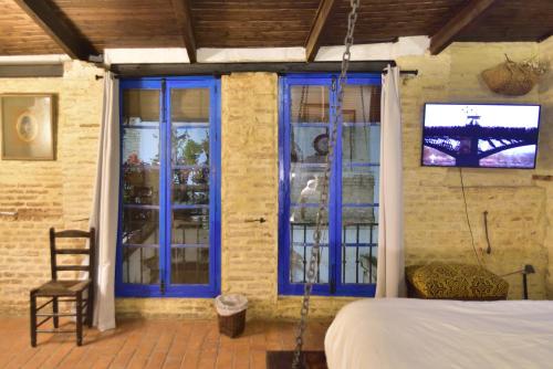 塞维利亚Suite Doña Inés Barrio Santacruz的客房设有蓝色窗户、一张床和电视。