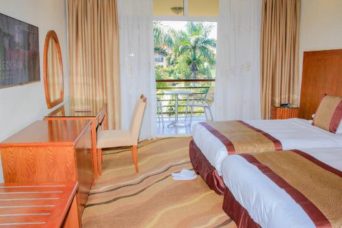 MbaleMbale Resort Hotel的酒店客房设有一张床、一张书桌和一个阳台。