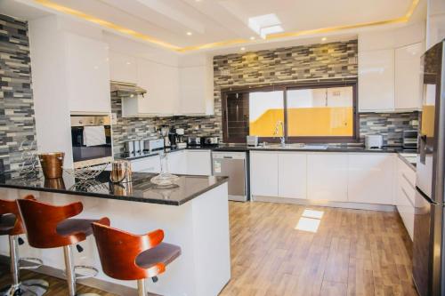 卢萨卡Z Apartment (4bedroom)的一间大厨房,配有白色橱柜和橙色酒吧凳子