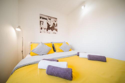 瓦拉日丁Apartment Sacramento centar Varaždin的一间卧室配有黄色的床,提供紫色和黄色枕头