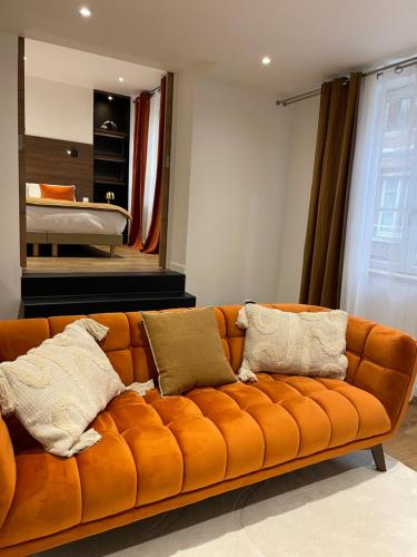 翁弗勒尔La Fleur de Sel的一张橙色的沙发,位于带床的房间