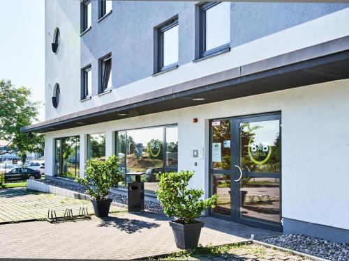 美因茨美因茨海彻斯黑姆住宿加早餐酒店的前方有玻璃门和盆栽植物的建筑