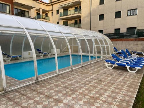 福斯特拉Apartamentos Playa Langosteira的大楼内带蓝色椅子的游泳池