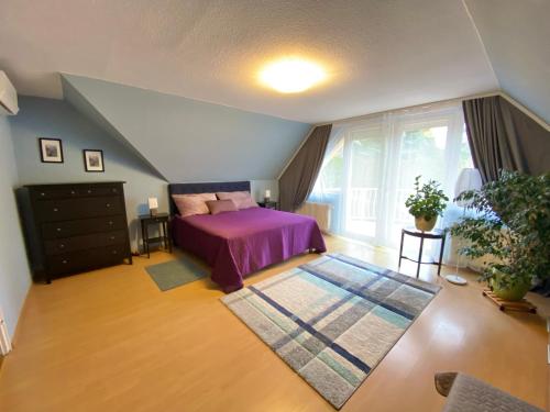CsömörTeresa Guest House的一间卧室设有紫色的床和大窗户