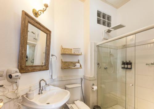 萨尔瓦多太阳神旅馆的白色的浴室设有水槽和淋浴。