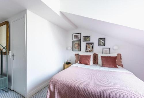 万塞讷Sauvage的白色卧室配有一张带粉红色床单的大床