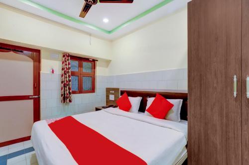 钦奈OYO Sam Guest House的一间卧室配有一张带红色枕头的大床