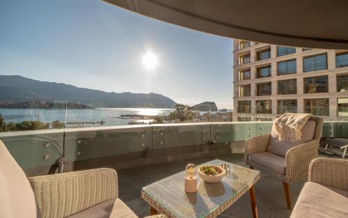 布德瓦Amare Luxury Apartments的阳台配有桌椅,享有水景。
