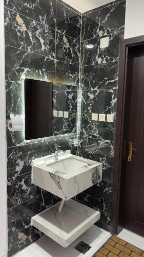 Al Bad‘فندق الاقامة السعيدة的黑色大理石浴室设有水槽和镜子