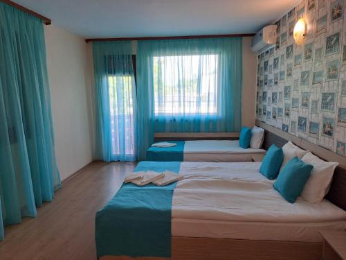 希典Къща за гости КАТИ的配有蓝色窗帘的客房内的两张床