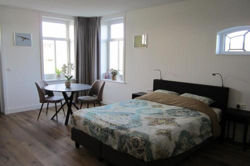 埃丹Aan de Dijk的卧室配有一张床和一张桌子及椅子