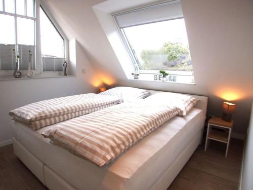万根沃格Boothäuser Living_art Wangerooge的卧室设有一张大床,设有两个窗户