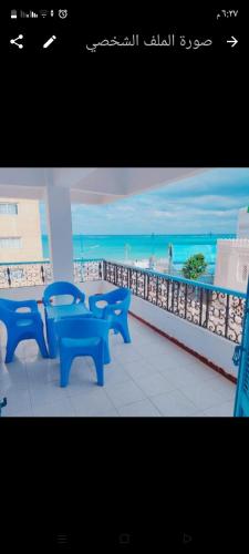 马特鲁港Queen Home Hotel的一组蓝色长椅,坐在俯瞰着海滩的阳台