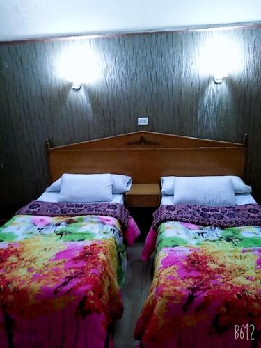 马特鲁港Queen Home Hotel的两张睡床彼此相邻,位于一个房间里