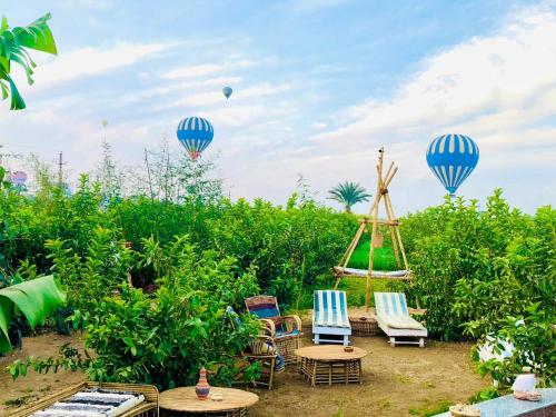 卢克索Bedouin Lodge Luxor的两个热气球飞越一个带桌椅的花园