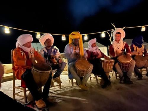 梅尔祖卡Desert Luxury Camp Experience的一群坐在椅子上弹鼓的人