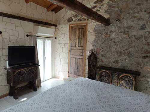 FontanLa petite tanière的一间卧室设有一张床、一台电视和石墙