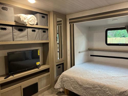 霍姆斯泰德Homestead RV的一间小卧室,配有一张床和一台平面电视