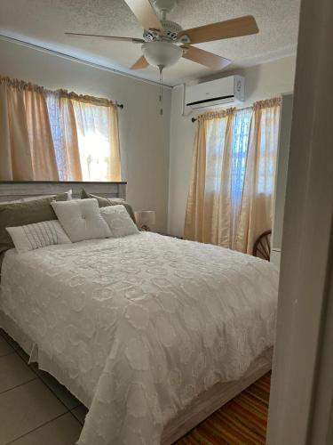 KoolbaaiELLO SUITES的卧室配有白色的床和吊扇